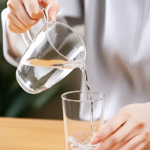 她从玻璃壶里倒水。