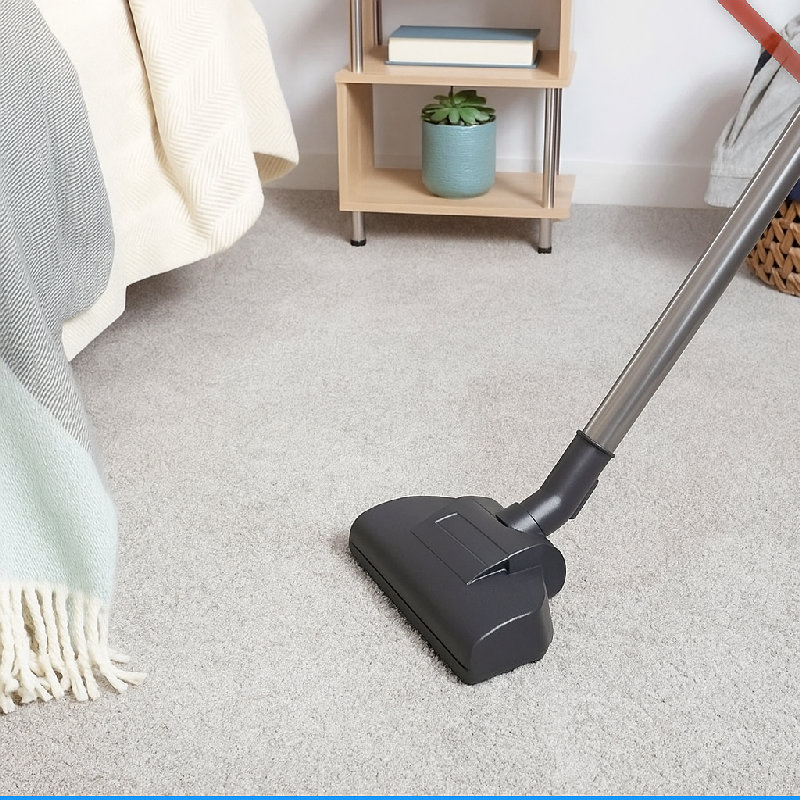 他用吸尘器清洁地毯。