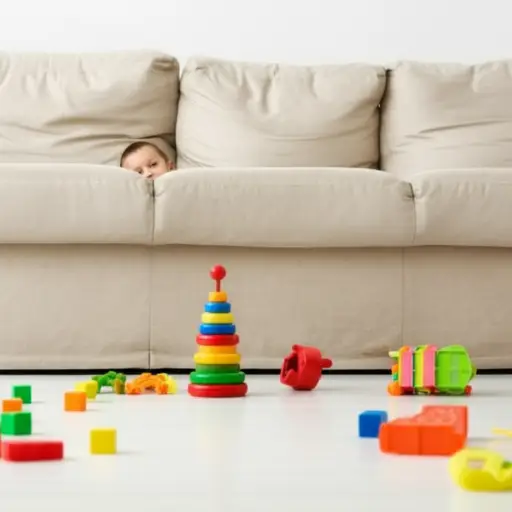 游戏时，那个孩子躲在沙发后面。