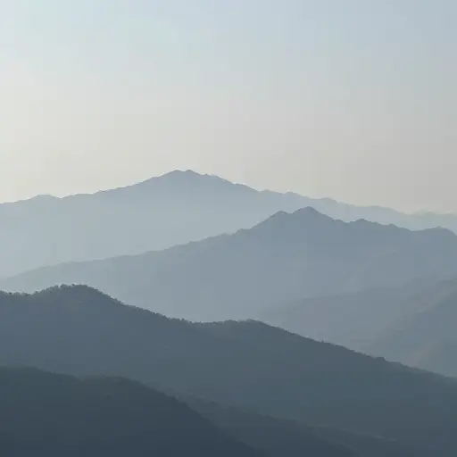 群山向远处绵延，逐渐消失在薄雾中。